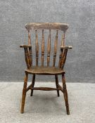 A 19th century oak Windsor style elbow chair having a curved top rail above a turned spindle back