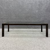 A contemporary exotic hardwood coffee table with an inset plate glass top over a canted frieze on