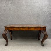 An early 20th century burr walnut dining table having a book match veneered top with a thumb moulded