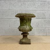 A 19th century Neoclassical composite stone urn of baluster form with a wide beaded rim over a