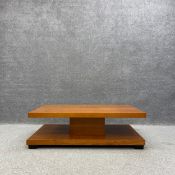 A contemporary cherry coffee table having a rectangular top on a central plinth over a lower shelf