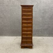 An Indonesian hardwood narrow chest of ten short drawers on bracket feet. H.134.5 W.40 D.42.5cm