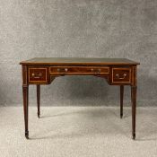 An Edwardian mahogany writing table having a tooled and gilt green leather top over an arrangement