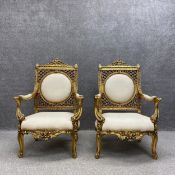 A pair of Louis XV style giltwood armchairs each having a scrolled cresting above an openwork and