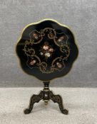 A Victorian style black lacquered tilt top table having a hand painted top decorated with flowers