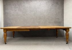 A Victorian oak extending dining table with three additional leaves on turned and fluted supports on