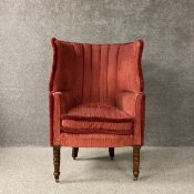 A late Georgian barrel back wing armchair with shaped back over a cushioned seat reupholstered in