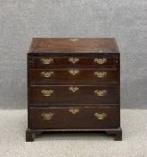 A Georgian oak bureau having a fall front above a fitted interior over four long graduating