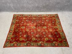 A large Persian woollen Tabriz rug with allover repeating foliate decoration over a burgundy