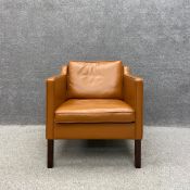 A contemporary Danish tan leather armchair on straight square teak supports by Stouby with a maker's