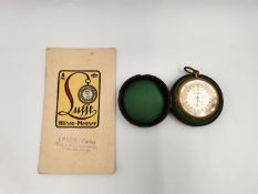 An early 20th century brass cased compensated pocket barometer with its original baize lined leather
