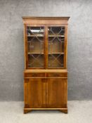 A 19th century style yew wood library bookcase with a dentil moulded cornice over a glazed and