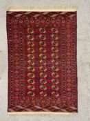 An early 20th century Tekke Turkmen wool rug having three rows of eleven guls over a madder red