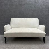 A late 19th century two seater sofa with a shaped back and outswept armrests newly re-upholstered in