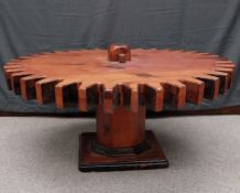 A mid-century stained pine cog wheel coffee table raised on an octagonal column on a stepped