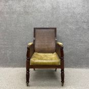 A Regency mahogany bergere library armchair with a curved and shaped back over green leather and
