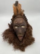 An African hand painted and carved tribal ceremonial mask/headdress, the top being inset with a