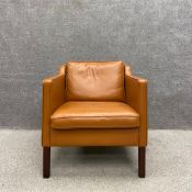 A contemporary Danish tan leather armchair on straight square teak supports by Stouby with a maker's