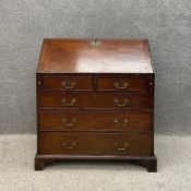 A Georgian mahogany writing bureau, the fall front with a pierced brass escutcheon opening on to a