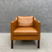 A contemporary Danish tan leather armchair on straight square teak supports by Stouby with a maker's