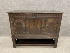 An 18th century oak coffer with a later hinged lid and a carved top rail over a