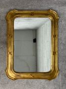 A mid century Italian giltwood wall mirror with a shaped, carved and moulded frame around a bevelled