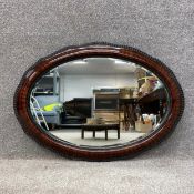 An Edwardian crossbanded mahogany wall mirror with an ebonised beaded trim surrounding an oval