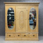 An Edwardian stripped pine wardrobe in four parts having a moulded cornice and a repeating bow and