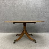 A Regency mahogany dining table having an oval crossbanded and inlaid top with a tilt action over