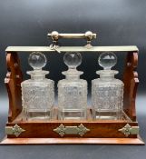 A late 19th century oak and silver plated three bottle tantalus with key and working locking