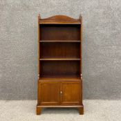 An Edwardian mahogany open bookcase with a shaped gallery above three shelves over two cabinet doors