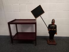 A vintage mahogany two-tiered trolley on casters along with a carved and painted policeman figure