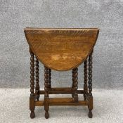 A late 19th/early 20th century oak drop leaf table with an oval thumb moulded top on turned,