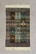 A small Persian silk Qum rug having twelve central panels with scrolling foliate motifs bordered