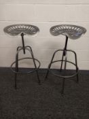 A pair of mid-century style industrial tractor seat counter stools with adjustable heights.