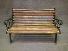 A contemporary painted cast iron garden bench in the 19th century style with scrolling openwork