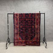 A Hamedan carpet having a repeating geometric pattern in iron red over a midnight ground