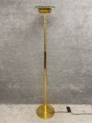 A contemporary brass standard lamp uplighter with a moulded floral design and a thick plate glass