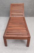 A contemporary teak reclining sun lounger with one end on wheels, along with a full length cushion