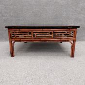 A vintage Oriental style bamboo coffee table with an ebonised and distressed top above a fretwork