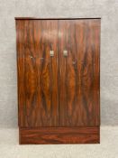 A mid-century faux rosewood cabinet with two metamorphic doors hinged at the sides to become a