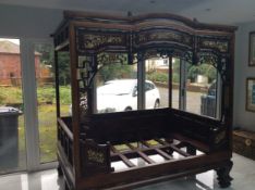 A Chinese four poster teak opium or marriage bed with a shaped frieze inlaid with bone, above a