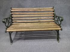 A contemporary painted cast iron garden bench in the 19th century style with scrolling openwork
