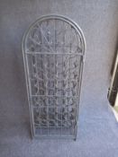 A painted wrought metal wine rack having forty individual bottle holders behind a lockable door with