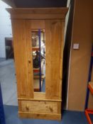 A C.1900 pine wardrobe having an angled cornice above a single mirrored door flanked by two panels