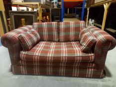 A contemporary two seater sofa with a rolled back and arms in a tartan fabric upholstery with