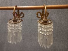 A pair of early 20th century Regency style brass wall lights with cut crystal hanging lustres.