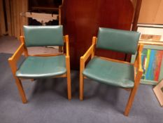 A pair of mid century oak framed lounge chairs in vinyl upholstery.