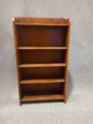 An early to mid century oak open bookcase with a shaped gallery above four shelves and a Binns of
