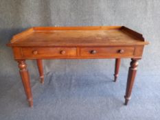 An early Victorian mahogany writing desk with a shaped gallery back over two drawers on turned and